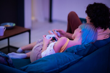 Happy couple playing video games at home during self isolation on a pandemic quarantine. Young man...