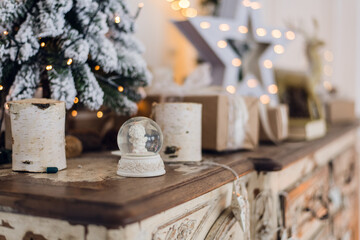 Magical Christmas snow globe with little angel statue inside. Christmas decoration around. Shallow...