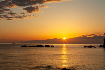 朝陽が雲と海をオレンジ色に染めて光の道をつくる