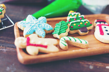 Sweet colourful Christmas cookies on wooden dish in kitchen at home. Merry Christmas and Happy New Year