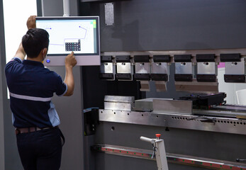 Industrial technician opearting CNC synchronize hydraulic press brake. Metalworking manufacturing factory