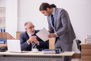 Old boss and young male assistant in the office