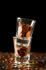 Concepts of finance, investing in assets with interest, dividend and profit. Coins are in the glass stacked on a black background.