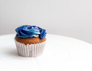 Vanilla cup cake with blue and white frosting on a white wrapper 