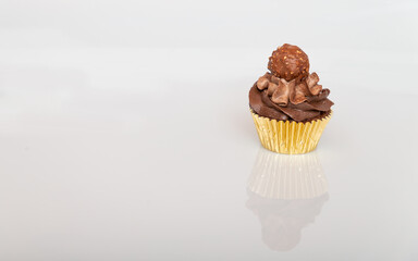 Cupcake with Chocolate frosting and a Chocolate boll on top in a gold wrapper