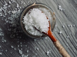 유리용기에 담긴 바다소금과 나무 숟가락 
