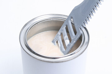 A man stirring white paint in a can on a white background. Renovation concept.