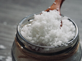 유리용기에 담긴 바다소금과 나무 숟가락 
