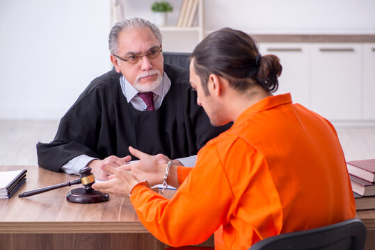 Old male judge meeting with young captive in courthouse
