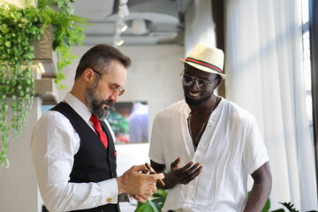 Caucasian businessman in formal wear and his African American friend in luxury tropical style hotel...