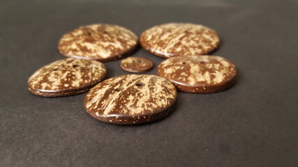 Flat large round coconut shell buttons, with one small button in the middle of the circular design. 