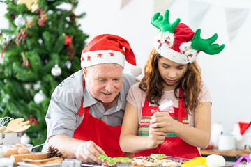 Happy family. Father and daughter wearing kitchen apron decorating Xmas cookies in the kitchen with Christmas tree at home. Cooking and Holiday concept. Merry Christmas and Happy New Year
