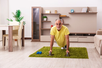 Aged man doing sport exercises at home