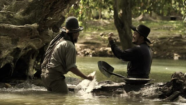 Cowboys, two men panning for gold by the river.