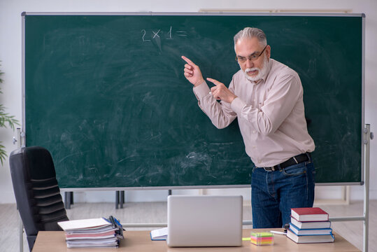 Old male teacher sitting in the classroom