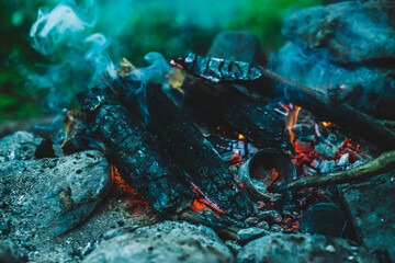 Vivid smoldered firewoods burned in fire close-up. Atmospheric warm background with orange flame of...