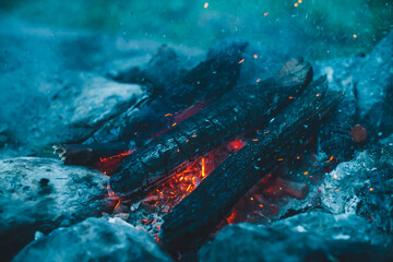 Vivid smoldered firewoods burned in fire close-up. Atmospheric warm background with orange flame of...