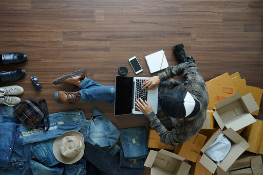  Top View Asian Man Selling Online Start Up Small Business Owner Working Laptop Computer, With Fashion Accessories And Postal Parcel On Wooden Floor From Home