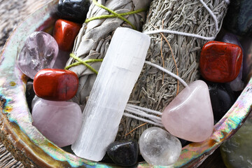 A close up image of two white sage bundles with several healing crystals in an abalone shell. 