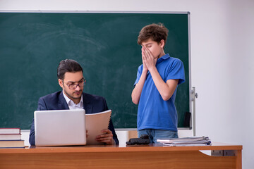 Young male teacher and schoolboy in the classroom