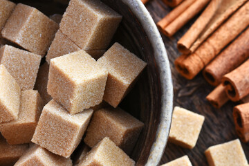 A close up image of brown sugar cubes and cinnamon sticks in a handmade pottery bowl. 