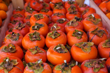 Background of ripe persimmons. Persimmon fruits are sold in the market. Persimmon is a delicious and healthy fruit. Fig persimmon close-up lies in rows.