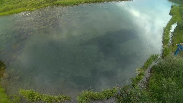 An angler casts for arctic grayling in the clear waters of Alaska's Gulkana River.