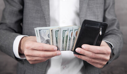 Businessman holding dollars with wallet.