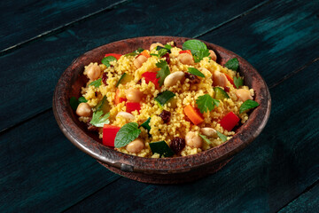 Couscous in the traditional tagine, with vegetables and herbs, on a dark rustic wooden background
