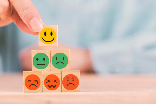 Hand chooses with happy smile face emoticon icons on Wooden Cube , good feedback rating for customer review survey