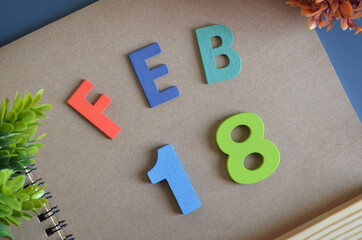February 18, Cover design in natural concept with a brown notebook and colorful wooden alphabet.