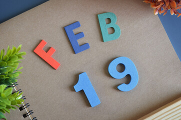 February 19, Cover design in natural concept with a brown notebook and colorful wooden alphabet.