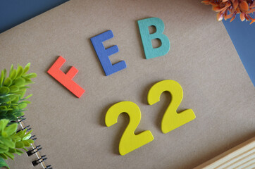 February 22, Cover design in natural concept with a brown notebook and colorful wooden alphabet.