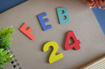 February 24, Cover design in natural concept with a brown notebook and colorful wooden alphabet.