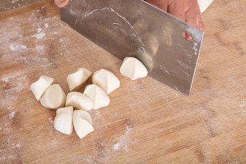 Cut the long strips of white noodles on the cutting board into small doughs with a kitchen knife