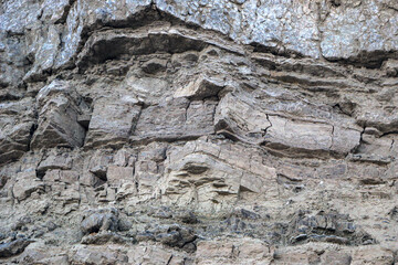 sandy-gypsum cut of the earth in quarry for the extraction of gypsum. Mountain textures of different soil layers with deposits of sand, clay, gypsum, quartz and gypsum ore, after erosion.