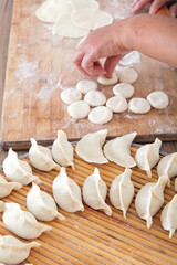 Dumplings wrapped on a circular tray and busy making scene in the background