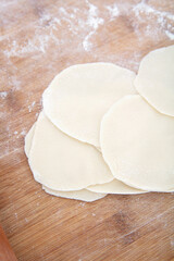 Close-up looking down on white flour dumpling wrappers on cutting board