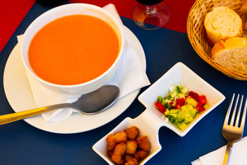 Spanish traditional cold soup gazpacho in bowl, served with baked breads and vegetables