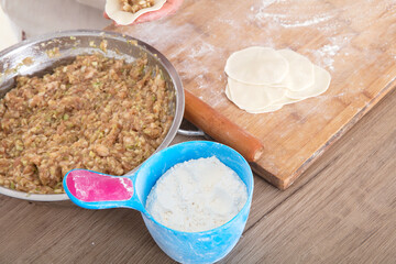 Meat and white noodles and pressed dumpling wrappers on the table