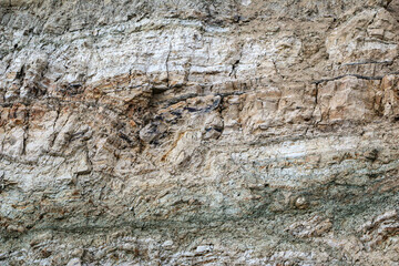 sandy-gypsum cut of the earth in quarry for the extraction of gypsum. Mountain textures of different soil layers with deposits of sand, clay, gypsum, quartz and gypsum ore, after erosion.
