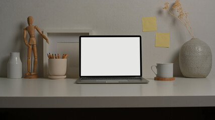 Worktable with laptop, supplies and decorations in home office room