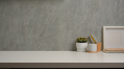 Workspace with decorations and copy space on white table with loft wall background
