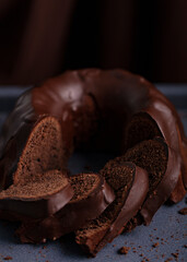 Dark chocolate cake covered with icing covered on a dark background. Selective focus.