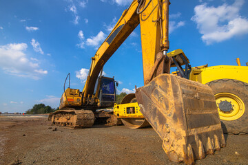 Backhoe and road roller on the ground at site construction.