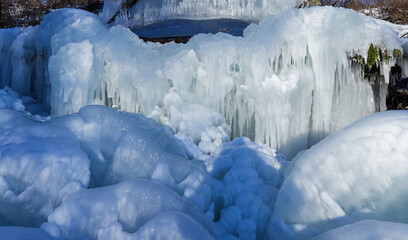 Stunning frozen icicles waterfall on a rocky mountain cliff on a winter day. The winter cascade is...