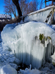 Stunning frozen icicles waterfall on a rocky mountain cliff on a winter day. The winter cascade is frozen in numerous white icicles. Waterfall falling past hundreds of icicles fantastic winter landsca
