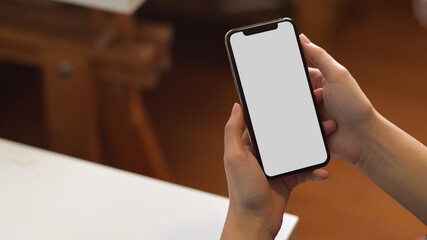 Close up view of female hands holding smartphone in office room