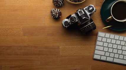Wooden table with camera, keyboard, coffee cup and copy space