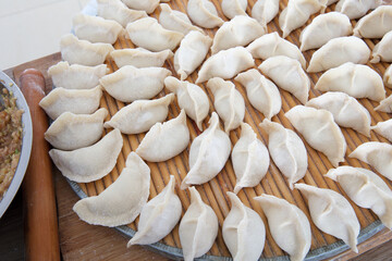 Looking down, neatly wrapped dumplings are placed on a circular tray